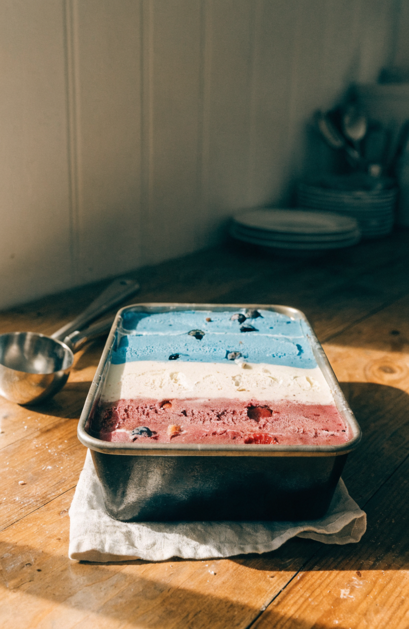 Scoop of no churn ice cream with red, white, and blue layers in a white bowl